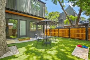 un patio con tavolo, sedie e ombrellone di Super Stunning Back House w Terrace in East Chavez ad Austin