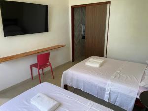 una habitación de hotel con 2 camas y una silla roja en Milagres do Camaragibe en Passo de Camarajibe