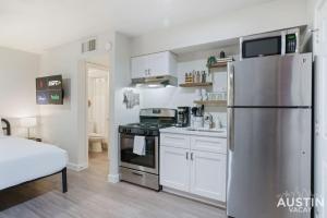 uma cozinha com um frigorífico de aço inoxidável e armários brancos em Cozy Newly Renovated King Sofa Bed and Smart TV em Austin
