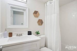 a white bathroom with a sink and a mirror at Cozy Newly Renovated King Sofa Bed and Smart TV in Austin