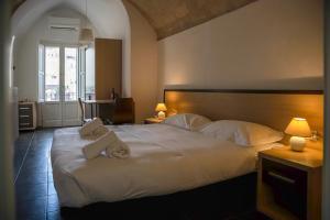 a bedroom with a large white bed with two towels at Residence Le Vie Del Mosto in Matera