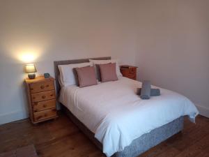 a bedroom with a white bed and a night stand at Large 4 Bedroom House in Norfolk Perfect for Families and Groups of Friends in Stoke Ferry