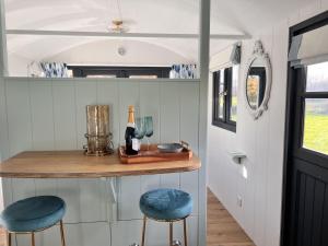 a small bar in a tiny house with two blue stools at Cattlestone Farm in West Chiltington