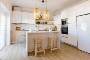 a kitchen with white cabinets and a island with stools at Caparica Sun Beach Villa in Charneca