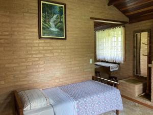 a bedroom with a bed and a picture on the wall at Pousada Colar de Ouro Chalés in Cunha