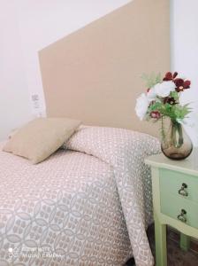 1 dormitorio con 1 cama con un jarrón de flores sobre una mesa en Hostal Buena Vista, en Vejer de la Frontera