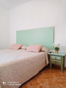 a bedroom with a bed with pink pillows and a table at Hostal Buena Vista in Vejer de la Frontera