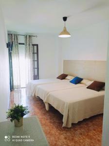 two beds in a white room with at Hostal Buena Vista in Vejer de la Frontera