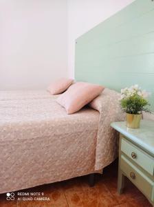 Un dormitorio con una cama con almohadas rosas y una mesa. en Hostal Buena Vista, en Vejer de la Frontera