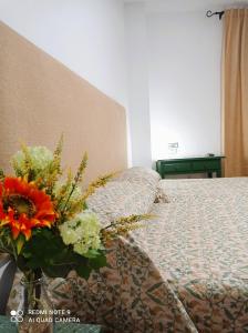 Un dormitorio con una cama con un jarrón de flores en Hostal Buena Vista, en Vejer de la Frontera
