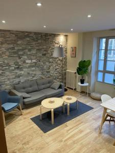 a living room with a couch and tables and a brick wall at T5 COEUR DE VILLE in Besançon