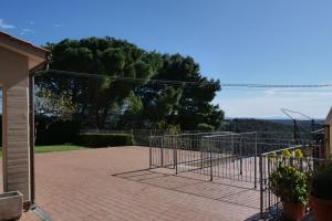 een metalen poort op een bakstenen patio met bomen op de achtergrond bij Casa vacanza Riparbella in Riparbella
