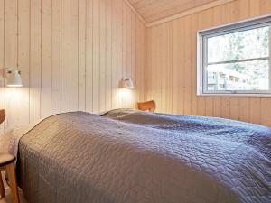 een slaapkamer met een bed en een raam bij Holiday home Nexø XLII in Neksø