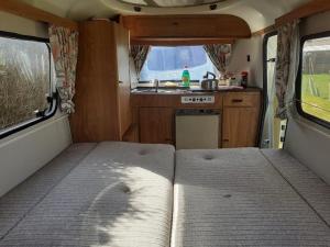 an interior of an rv with a bed and a kitchen at Sundial Cottage Eriba Caravan in Norwich