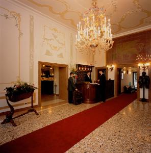 a lobby with a chandelier and people standing at a counter at UNAHOTELS Ala Venezia-Adults 16 in Venice