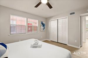 um quarto com uma cama branca e uma ventoinha de tecto em Walk to Restaurants or Cook in Subway Tile Kitchen em Austin