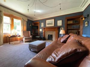 a living room with a leather couch and a fireplace at Balloan House in Dornoch