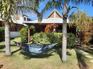 a hammock between two palm trees in front of a house at LES PECHEURS DU LAGON in Saint-Leu