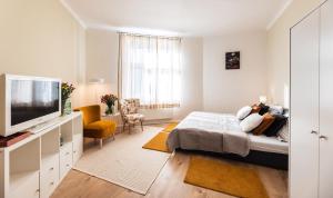 een witte slaapkamer met een bed en een televisie bij Silvie Apartments - Šmeralova in Olomouc
