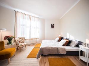 een witte slaapkamer met een groot bed en een stoel bij Silvie Apartments - Šmeralova in Olomouc