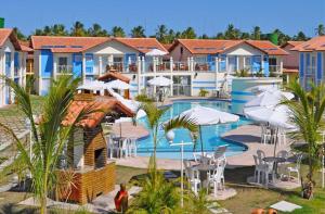 ein Resort mit einem Pool mit Tischen und Sonnenschirmen in der Unterkunft DUPLEX 2 SUÍTES MONT SIÃO in Porto Seguro