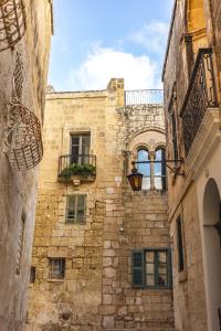 - un vieux bâtiment en pierre avec un balcon et des fenêtres dans l'établissement Palazzo Bifora, à Mdina