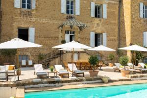 Ornézan的住宿－Stunning refurbished Chateau in South West France，一座带椅子和遮阳伞的游泳池位于一座建筑旁边