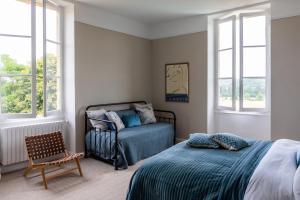 a bedroom with a bed and a chair and windows at Stunning refurbished Chateau in South West France in Ornézan