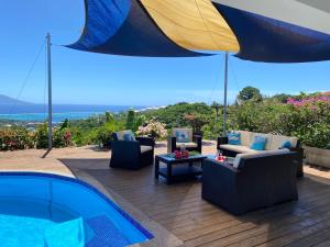 a patio with chairs and a swimming pool and an umbrella at Villa Green in Punaauia