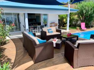 a patio with wicker furniture next to a swimming pool at Villa Green in Punaauia