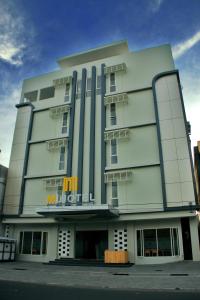 M Hotel في ماتارام: مبنى ابيض كبير عليه لافته