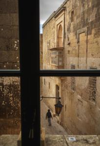 a view from a window of a man walking down an alley at Palazzo Bifora in Mdina