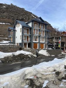 a large apartment building on a hill with snow at The Bulevar - Whispering Willows in Sissu