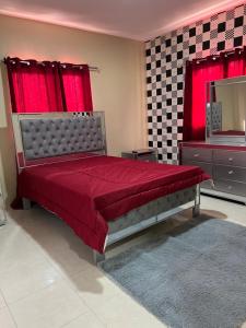 1 dormitorio con cama roja y espejo en Edificio ramirez, en Baní