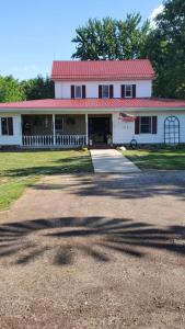 Casa blanca con techo rojo y entrada en The FarmHouse Inn Bed and Breakfast, en Nappanee