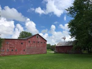 a red barn in a field with a tree at The FarmHouse Inn Bed and Breakfast in Nappanee
