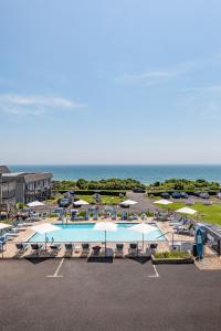 a parking lot with a pool and umbrellas and the ocean at Hartman's Briney Breezes Beach Resort in Montauk