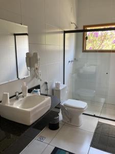 La salle de bains blanche est pourvue d'un lavabo et de toilettes. dans l'établissement Pousada Colar de Ouro, à Cunha