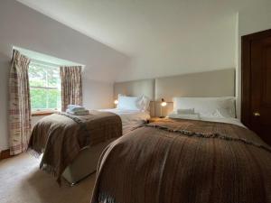 um quarto com 2 camas e uma janela em Balloan Cottage em Dornoch