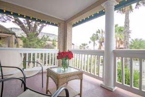 a porch with a table with a vase of flowers on it at Inn on Charlotte in Saint Augustine