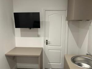 La salle de bains est pourvue d'un lavabo et d'une porte avec une télévision. dans l'établissement Unique Modern, 1 Bed Flat, 15 Mins To Central London, à Hendon