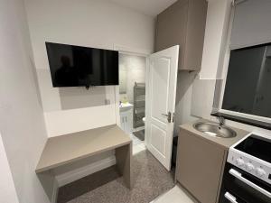 a small kitchen with a sink and a tv on the wall at Unique Modern, 1 Bed Flat, 15 Mins To Central London in Hendon