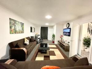 ein Wohnzimmer mit einem Sofa und einem TV in der Unterkunft 4 Bedrooms, 3 bathrooms , Reception, Kitchen, Garden, FullHouse in London