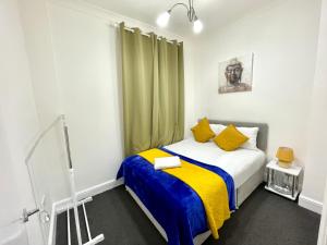ein Schlafzimmer mit einem Bett mit einer gelben und blauen Decke in der Unterkunft 4 Bedrooms, 3 bathrooms , Reception, Kitchen, Garden, FullHouse in London
