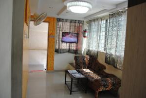 ein Wohnzimmer mit einem Sofa, einem Tisch und Fenstern in der Unterkunft Just Guest House, Chennai Airport in Chennai