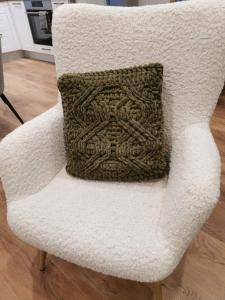 a white chair with a crochet pillow on it at Лиловата Къща in Kalofer