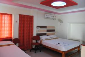 a bedroom with two beds and a window and a ceiling at Just Guest House, Chennai Airport in Chennai