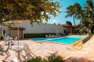 a swimming pool with a table and chairs next to a house at @euamotemporada Cumaru APT 207 - 100m da Praia in Marechal Deodoro