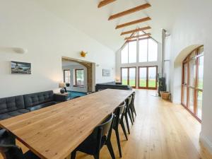 a large wooden table in a living room with a couch at Balloan Steading West in Dornoch