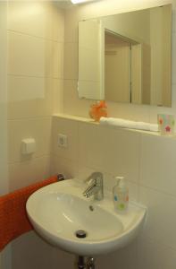 La salle de bains blanche est pourvue d'un lavabo et d'un miroir. dans l'établissement GWG City Apartments II, à Halle-sur-Saale